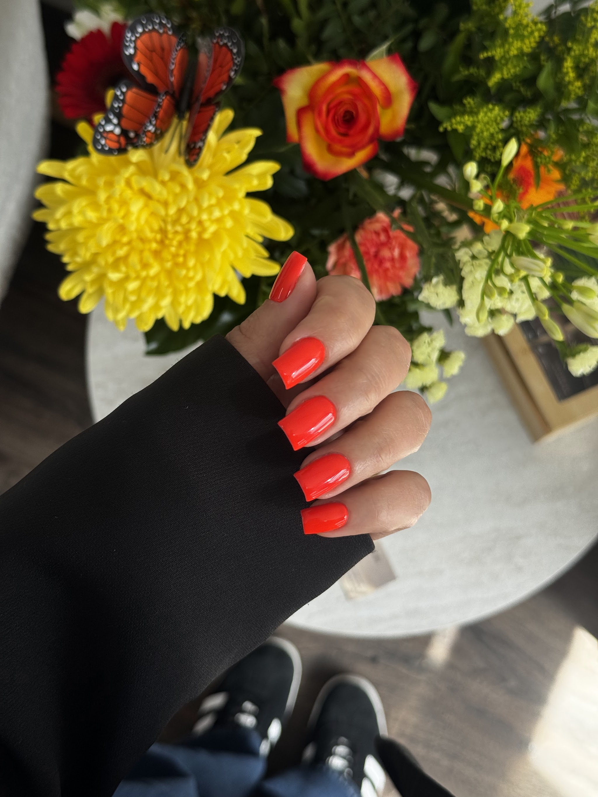Helderrode manicure bij een kleurrijk boeket